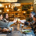 A group of friends toast colourful cocktails over pizza, wings and salad inside the cosy and stylish dining space at Racks—perfect for group catch-ups and private parties in Clifton.